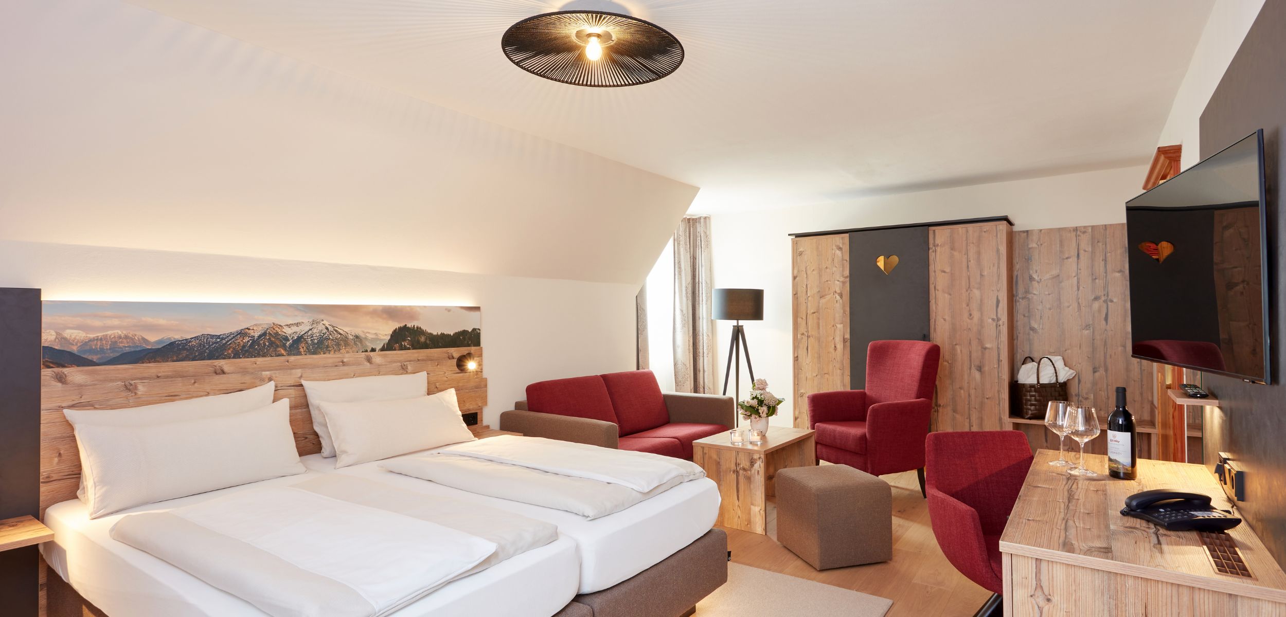 Moderne Zimmer im Hotel Alpenglück für den perfekten Familienurlaub in den Alpen Ein modernes Zimmer im Hotel Alpenglück mit zwei Betten, gemütlichen Sitzmöbeln und Alpenblick, ideal für einen Familienurlaub in den Bergen.