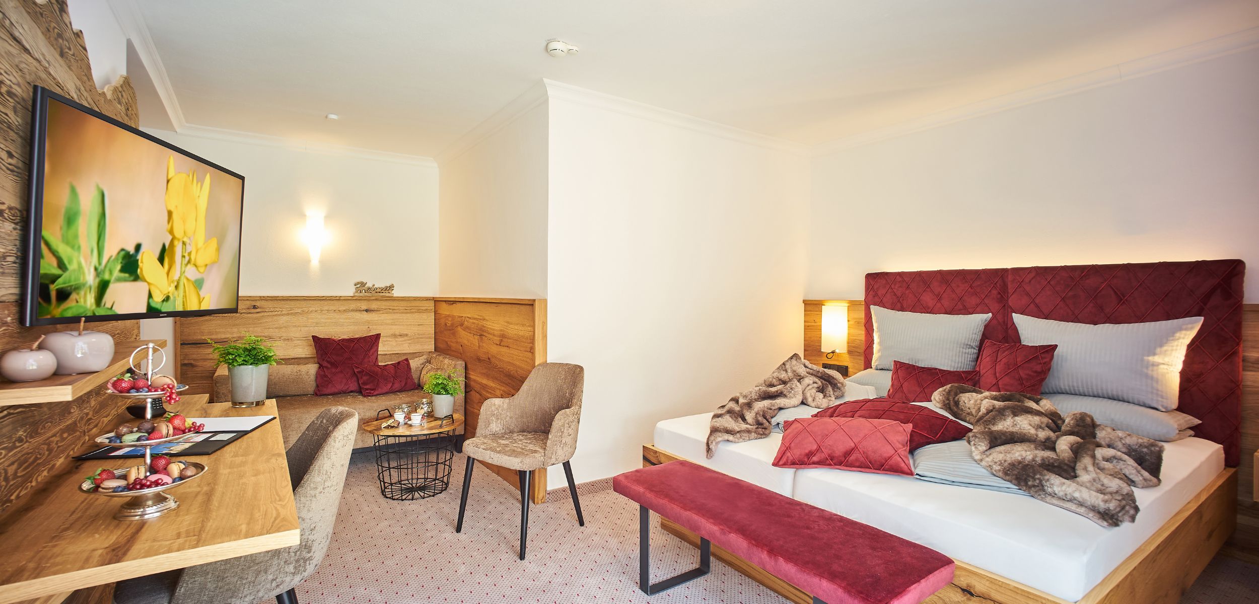 Gemütliches Zimmer im Hotel Alpenglück mit modernen Möbeln und einladendem Ambiente Modernes Zimmer im Hotel Alpenglück, ausgestattet mit einem Doppelbett, gemütlicher Sitzecke und Dekoration, ideal für einen Familienurlaub.