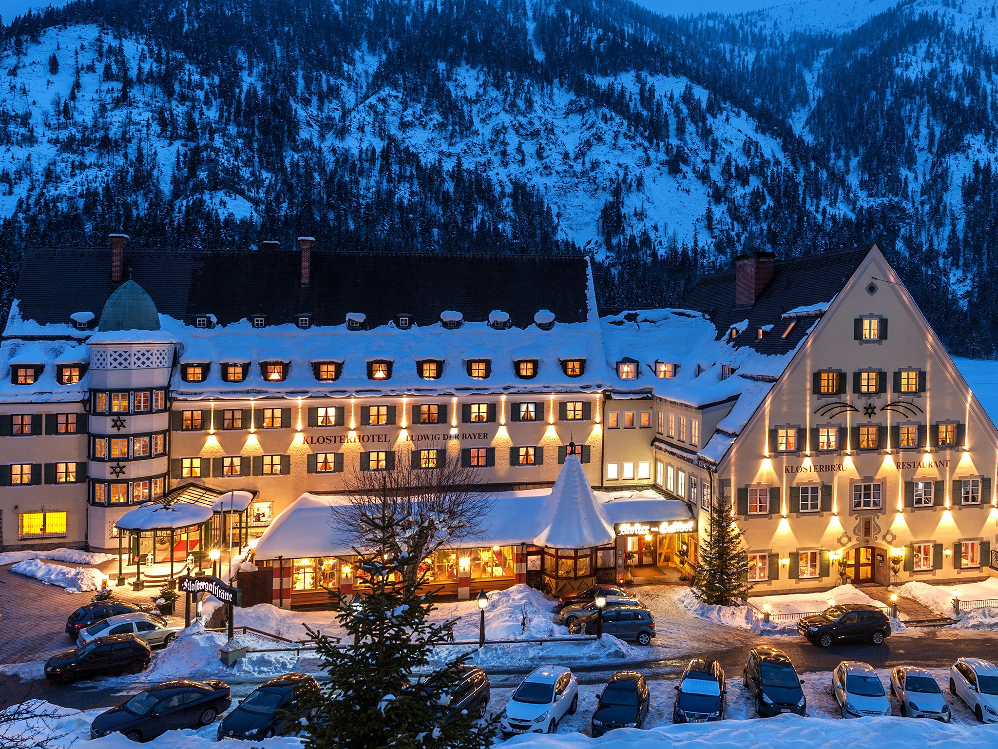 Das Klosterhotel Ludwig der Bayer in Bayern, umgeben von Schnee, mit beleuchteten Fenstern und schneebedeckten Dächern, ideal für Winterurlaub.