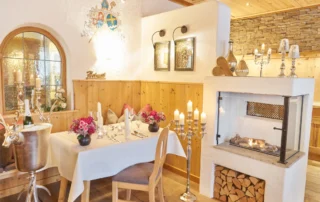 Ein eleganter Tisch im Restaurant mit Holzverkleidung, Blumenarrangement und Kerzen, perfekt für romantische Abendessen.