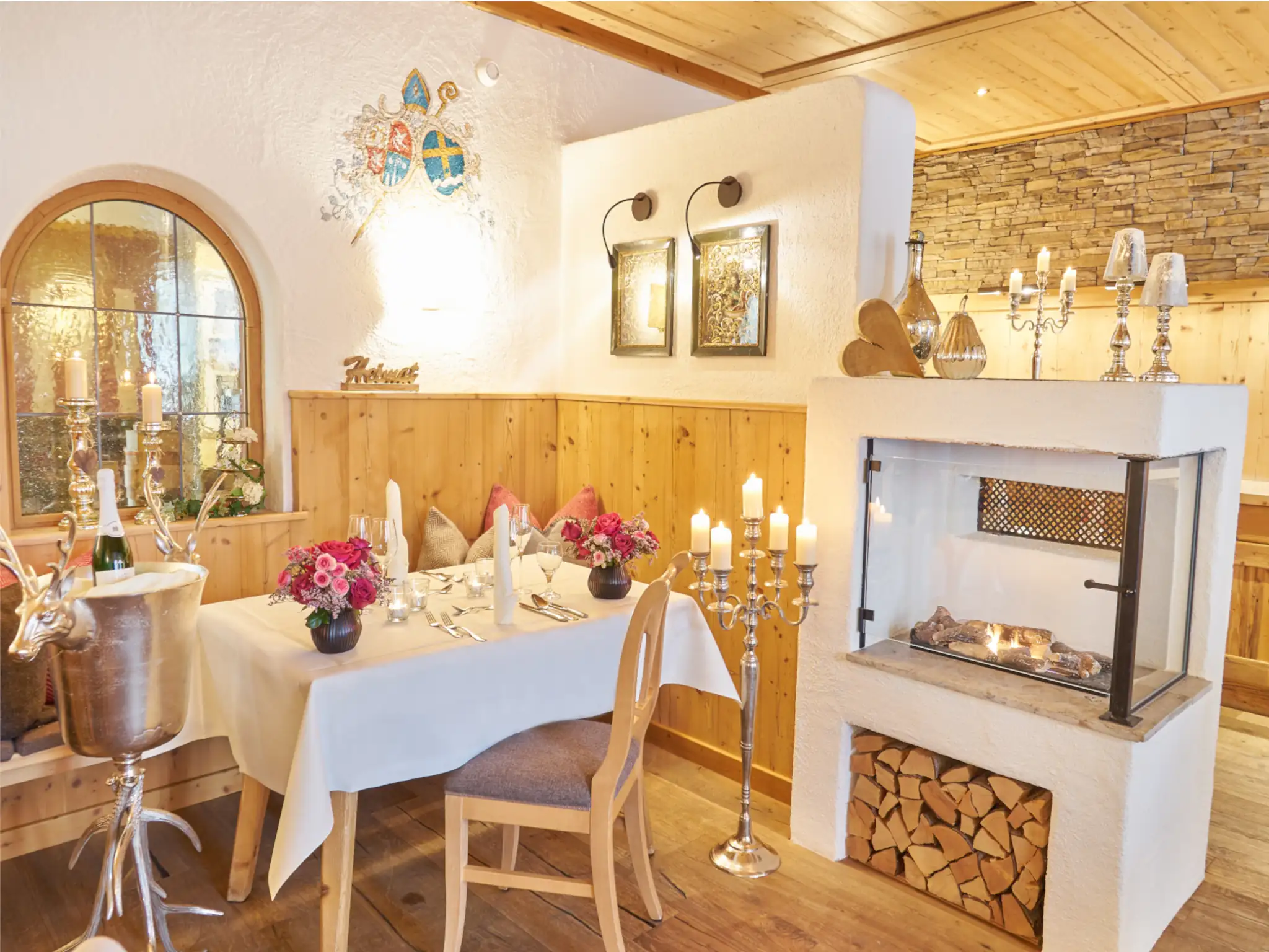 Ein eleganter Tisch im Restaurant mit Holzverkleidung, Blumenarrangement und Kerzen, perfekt für romantische Abendessen.