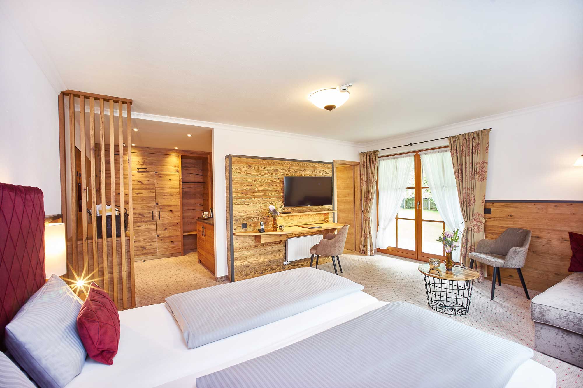 Gemütliches Hotelzimmer im Hotel Alpenglück, ausgestattet mit einem Doppelbett, Schreibtisch, TV und Blick auf die Natur.